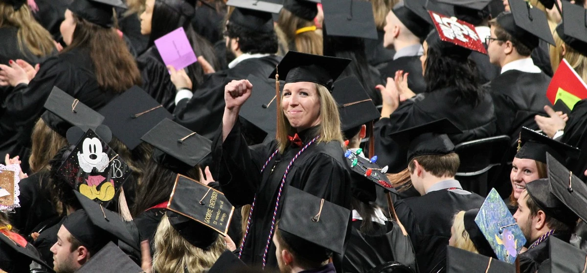 At Commencement, a graduate in a sea of students raises her arm in celebration of her accomplishments.