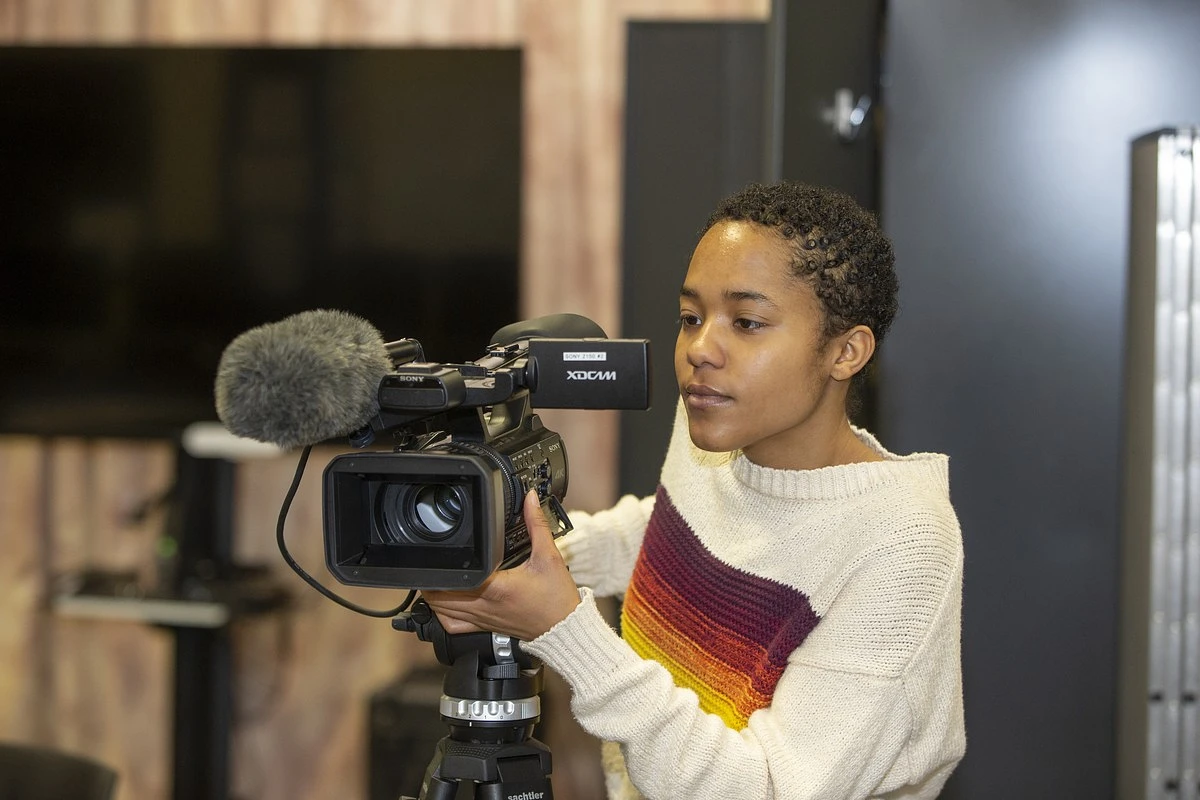 A female student behind a video camera