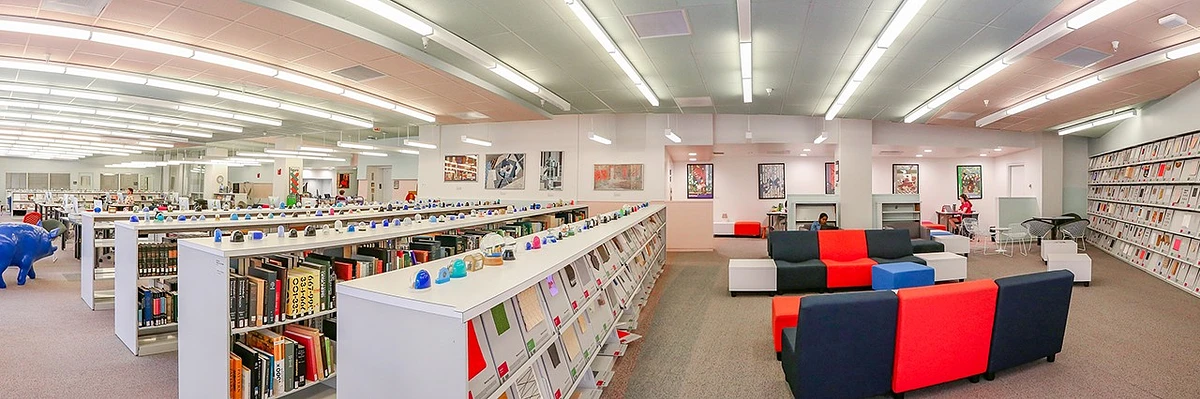 A panoramic photo of bookshelves and chairs in the DAAP library
